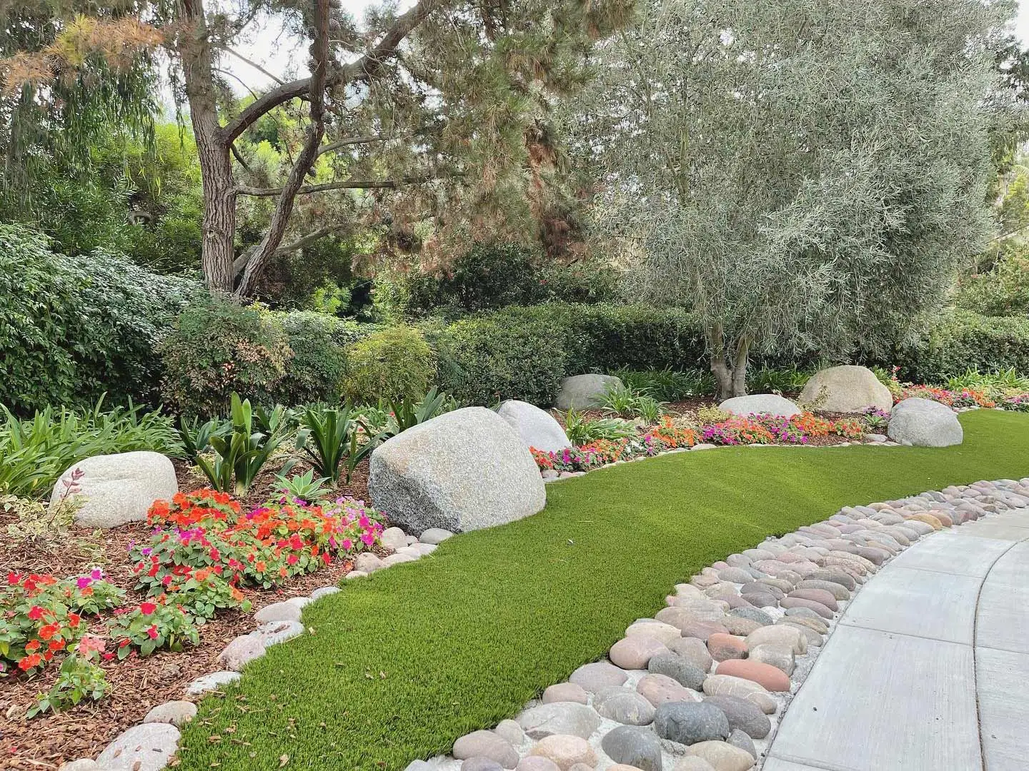 Landscape bed with plantings and boulders around a driveway near San Diego, CA.